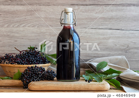 A bottle of black elder syrup with elderberries A bottle of black elder syrup with elderberries 46846949