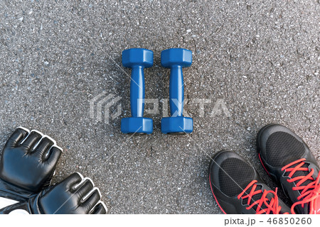 Boxing sports items. Cropped photo of dumbbells, gloves and sportive shoes Boxing sports items. Cropped photo of dumbbells, gloves and sportive shoes 46850260