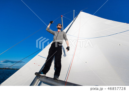 confident captain of sail boat standing and looking out to sea confident captain of sail boat standing and looking out to sea 46857728