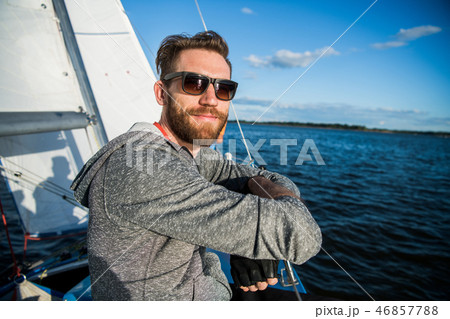 Nice happy bearded man sailor thumbing up and evincing positivity while at his yacht or boat on a Nice happy bearded man sailor thumbing up and evincing positivity while at his yacht or boat on a 46857788