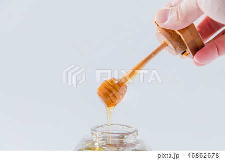 ハニーは、白い背景の上に木製蜂蜜ディッパーから滴ります 46862678