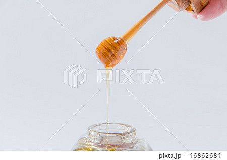 ハニーは、白い背景の上に木製蜂蜜ディッパーから滴ります 46862684