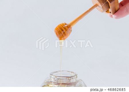 ハニーは、白い背景の上に木製蜂蜜ディッパーから滴ります 46862685