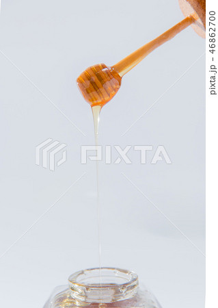 ハニーは、白い背景の上に木製蜂蜜ディッパーから滴ります ハニーは、白い背景の上に木製蜂蜜ディッパーから滴ります 46862700
