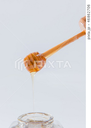 ハニーは、白い背景の上に木製蜂蜜ディッパーから滴ります 46862706