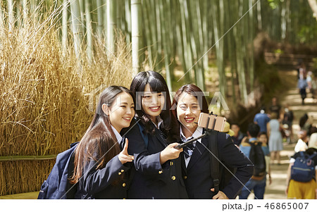 竹林の坂の上で自撮り写真を撮る三人の女子高生の写真素材