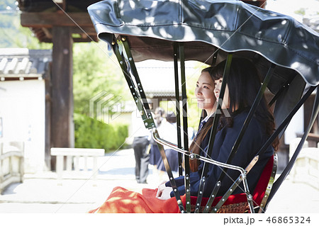 お寺の前で停車する人力車に乗る二人の女子高生 お寺の前で停車する人力車に乗る二人の女子高生 46865324