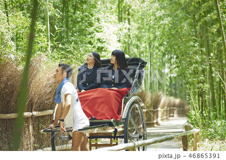 竹林を行く人力車に乗る二人の女子高生 46865391