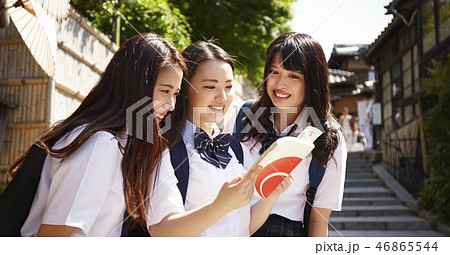 ガイドブックを手に街を散策する三人の女子高生 ガイドブックを手に街を散策する三人の女子高生 46865544