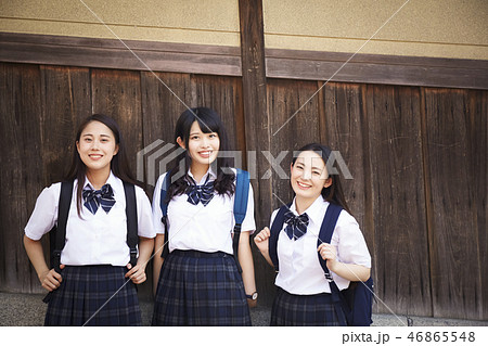 木塀の前に立つ三人の女子高生 46865548