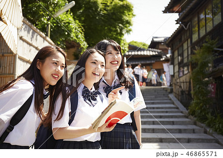 ガイドブックを手に街を散策する三人の女子高生 ガイドブックを手に街を散策する三人の女子高生 46865571
