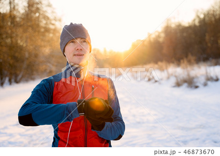 Runner wearing warm sporty clothes in headphones looks at a modern smart clock 46873670