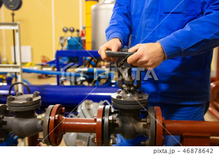 Production worker operates valve on pipeline Production worker operates valve on pipeline 46878642