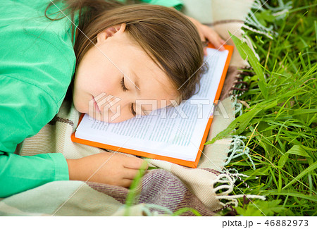 Girl is sleeping on her book outdoors Girl is sleeping on her book outdoors 46882973