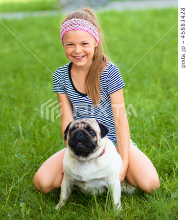 Little girl and her pug dog on green grass 46883428