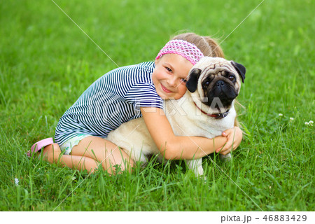 Little girl and her pug dog on green grass Little girl and her pug dog on green grass 46883429