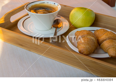 Delicious Breakfast on the balcony in the sunlight, with coffee, croissants, Apple on a wooden tray 46884084