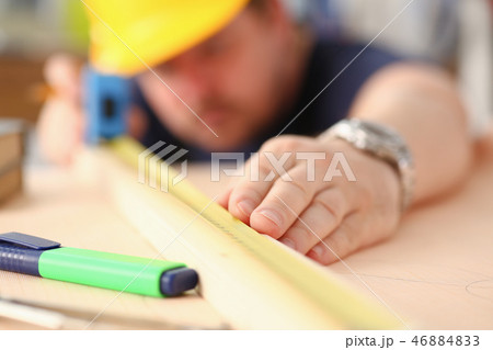 Arms of worker measuring wooden bar Arms of worker measuring wooden bar 46884833
