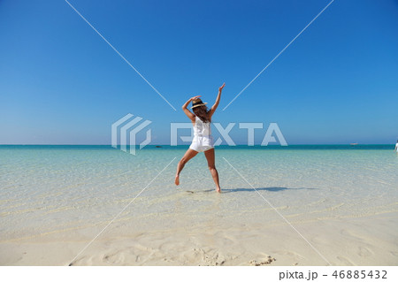 綺麗な海でジャンプする女性の後ろ姿 46885432