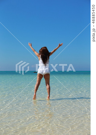 綺麗な海でジャンプする女性の後ろ姿 46885450