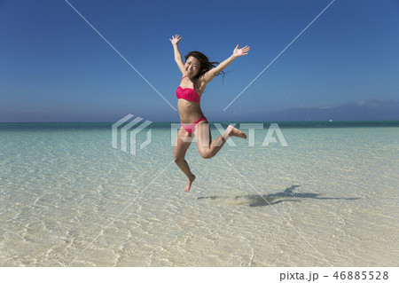 海でジャンプする女の子 正面の写真素材