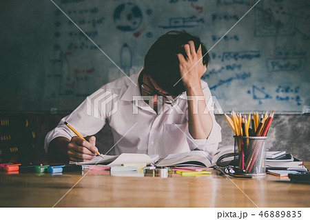 Young Asian student man sitting at desk in home studying and rea Young Asian student man sitting at desk in home studying and rea 46889835