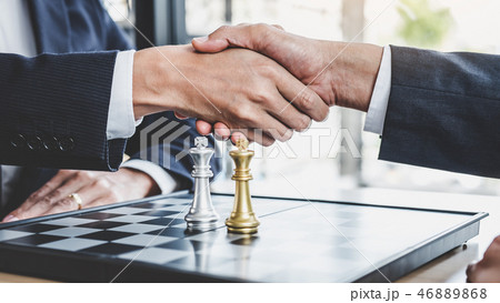 Two Businessman shaking hands after end playing chess game reach 46889868
