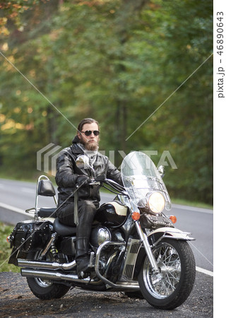 Bearded biker in black leather jacket on modern motorcycle on country roadside. 46890643