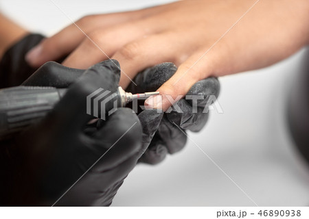 Close-up of professional beautician hands working with electric drill file on client fingernails. Close-up of professional beautician hands working with electric drill file on client fingernails. 46890938