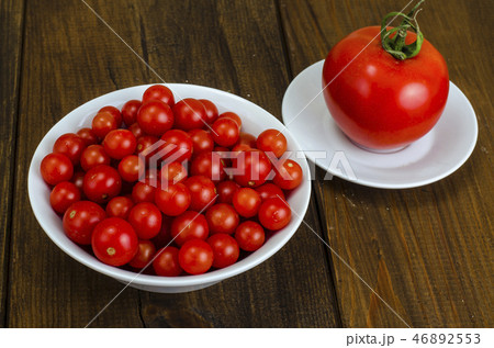 Small red cherry tomatoes in white bowl on wooden 46892553