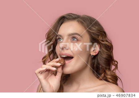beauty portrait of a cute girl in act to eat a chocolate candy beauty portrait of a cute girl in act to eat a chocolate candy 46907834