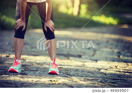 Tired female runner taking a rest after running Tired female runner taking a rest after running 46909907
