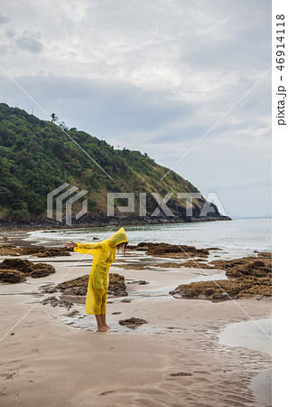 Woman wearing a yellow raincoat on the beach Woman wearing a yellow raincoat on the beach 46914118