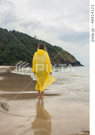 Woman wearing a yellow raincoat on the beach Woman wearing a yellow raincoat on the beach 46914121