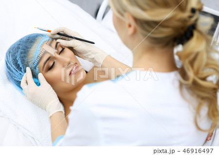 Professional beautician is going to correct eyebrow line at woman face using cosmetic ruler 46916497