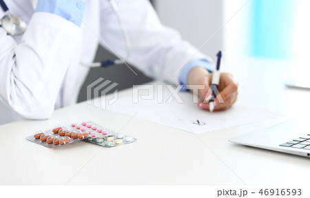 Female doctor filling up prescription form while sitting at the desk in hospital closeup. Healthcar Female doctor filling up prescription form while sitting at the desk in hospital closeup. Healthcar 46916593