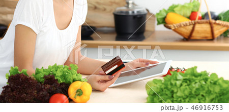 Beautiful Hispanic woman cooking while using tablet computer in kitchen or making online shopping Beautiful Hispanic woman cooking while using tablet computer in kitchen or making online shopping 46916753