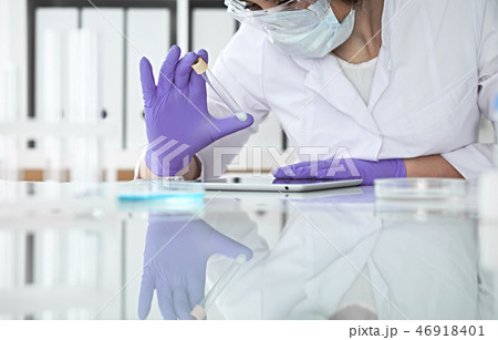 Close-up of professional female scientist in protective eyeglasses making experiment with reagents Close-up of professional female scientist in protective eyeglasses making experiment with reagents 46918401
