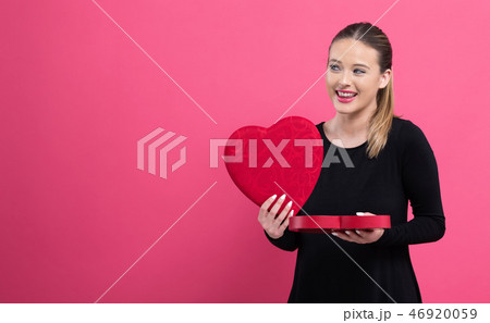 Young woman holding a big heart gift box 46920059