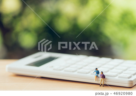 Miniature people sitting on white calculator Miniature people sitting on white calculator 46920980