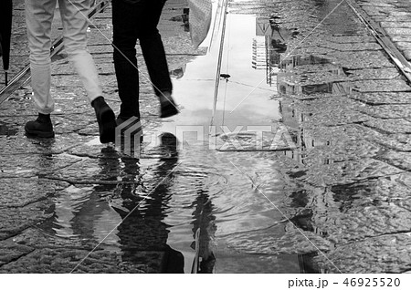 雨上がりの水たまりに描く足跡 ヨーロッパの街角の写真素材