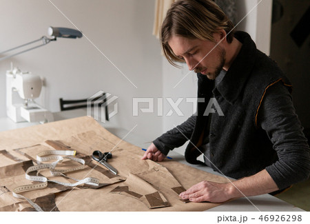 Male tailor creating clothing pattern while working at workplace Male tailor creating clothing pattern while working at workplace 46926298