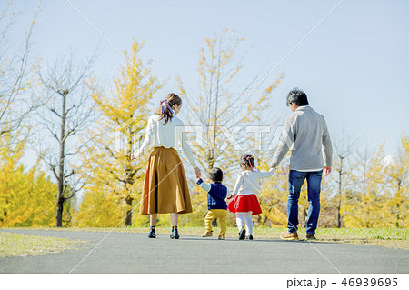 秋の公園で遊ぶ4人家族の後ろ姿の写真素材