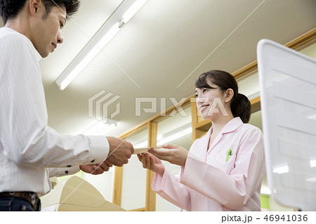 調剤薬局で薬を渡す薬剤師女性 46941036