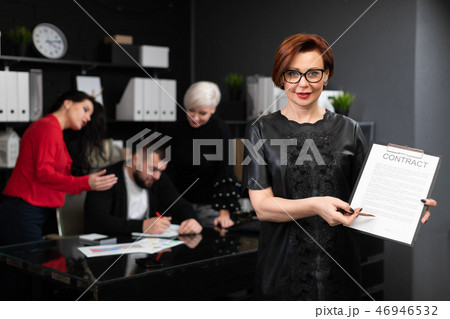 Businesswoman with pen and contract on background of Office workers discuss the project Businesswoman with pen and contract on background of Office workers discuss the project 46946532