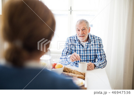 A senior couple sitting at the table at home, having breakfast. 46947536