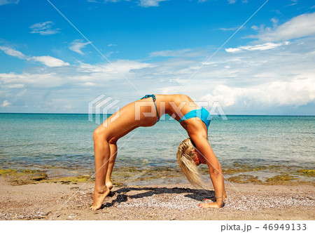 young woman on beach doing fitness yoga exercise. Acroyoga element for strength and balance 46949133
