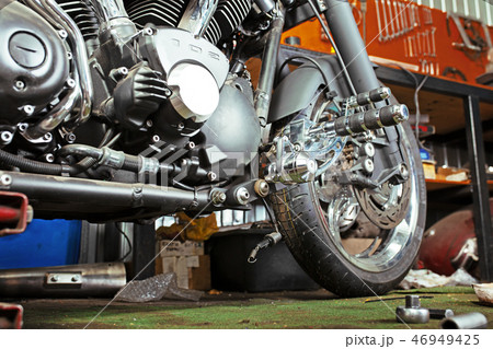 Cropped close up shot of beautiful and custom made motorcycle in the workshop Cropped close up shot of beautiful and custom made motorcycle in the workshop 46949425