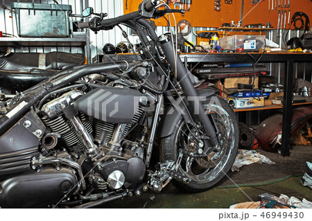 Cropped close up shot of beautiful and custom made motorcycle in the workshop Cropped close up shot of beautiful and custom made motorcycle in the workshop 46949430