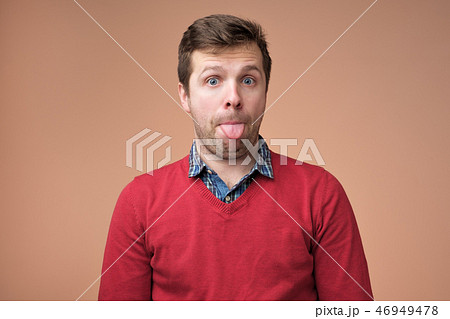 man sticking tongue out with funny expression. man sticking tongue out with funny expression. 46949478